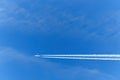 A passenger plane flies against a blue sky. White trace from the turbines of the aircraft. Royalty Free Stock Photo