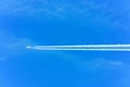 A passenger plane flies against a blue sky. White trace from the turbines of the aircraft. Royalty Free Stock Photo