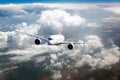Passenger plane flies high in the blue sky above the clouds. Front view. Royalty Free Stock Photo