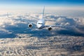 The passenger plane in flight. Aircraft flies high in the blue sky over clouds. Front view Royalty Free Stock Photo