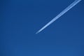 Passenger plane flying at high altitude through clear blue sky leaving two dense white trails Royalty Free Stock Photo