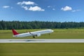 Passenger plane takes off from airport runway in forest Royalty Free Stock Photo