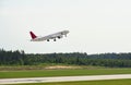 Passenger plane takes off from airport runway in forest Royalty Free Stock Photo