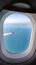 Wing of commercial airplane view from right the window of the plane flying above the clouds on blue sky Royalty Free Stock Photo