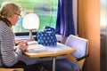 A passenger reading a book sitting at the dining car of a Greek