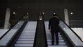 Passenger riding on the escalator up to the station of the ground metro. Media. Rear view of a young businessman on the Royalty Free Stock Photo