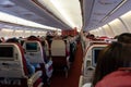 Passenger seat, Interior of airplane with passengers sitting on seats and stewardess walking the aisle in background