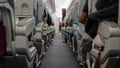 Passenger seat, Interior of airplane with passengers sitting on seats and stewardess walking the aisle in background Royalty Free Stock Photo