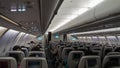 Passenger seat, Interior of airplane with passengers sitting on seats and stewardess walking the aisle in background Royalty Free Stock Photo