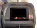 Passenger seat of plane with blank empty black monitor screen, and no smoking allowed sign Royalty Free Stock Photo