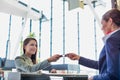 Passenger service agent giving boarding pass to young attractive businesswoman after check in at airport