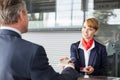 Passenger service agent giving businessman passport and boarding pass in check in area at airport Royalty Free Stock Photo