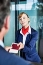 Passenger service agent giving businessman passport and boarding pass in check in area at airport Royalty Free Stock Photo