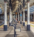 A passenger sits on a bench on a railway station platform with columns on each side Royalty Free Stock Photo