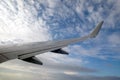 Passenger supersonic plane wing high moving from right to left in blue sky with clouds Royalty Free Stock Photo