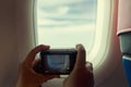 Passenger take a photo graph the beautiful view from porthole of airplane on sky with clouds under sun light Royalty Free Stock Photo