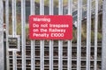 Passenger warning sign at railway train station stating do not trespass or penalty fine will be issued if you cross the rail line