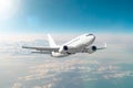 Passenger white airplane flies in a blue sky with a bright sun.