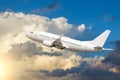 Passenger white airplane takes off against a background of cumulus clouds at sunset.