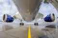 Passenger wide-body plane is parked on the airport apron. Aircraft fuselage, engine and main landing gear