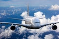 The passenger wide body plane flies high in the blue sky above clouds. Airplane closeup front view