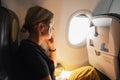 Passenger woman is flying in plane. Girl sitting in airplane looking out window going on trip vacation travel. Traveling