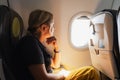 Passenger woman is flying in plane. Girl sitting in airplane looking out window going on trip vacation travel. Traveling