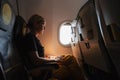 Passenger woman is flying in plane. Girl sitting in airplane looking out window going on trip vacation travel. Traveling