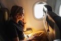 Passenger woman is flying in plane. Girl sitting in airplane looking out window going on trip vacation travel. Traveling