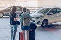 Passengers with big roller luggage stand to wait for the car to pick up