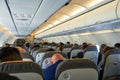 Passengers and crew sitting on airplane seats, view of the passengers and attendants inside cabin