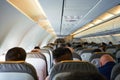 Passengers and crew sitting on airplane seats, view of the passengers and attendants inside cabin