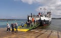 Passengers disembark from a small ferry onto the shore of the Isle of Iona, UK