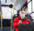 Passengers protecting by medical masks traveling by public transpost, sitting on bus. Royalty Free Stock Photo