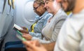 Passengers reading book and using mobile smartphones during airplane trip Royalty Free Stock Photo