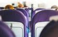 Passengers are sitting in the blue armchairs of the aircraft during the flight, the view from the back of tourists flying into Royalty Free Stock Photo