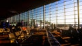 Passengers sitting on chairs in airport terminal, spacious sunlit waiting lounge