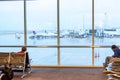 Passengers sitting and watching out a window in airport Royalty Free Stock Photo