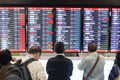 Passengers standing in front of arrivals board .