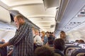 Passengers standing to disembark from an airplane.