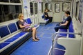 Passengers traveling in a half-empty metro car. A middle-aged woman and two men. Woman reading an e-book