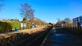 passengers waiting for a train on the platform in a typical rural British railway station while a train approaches under Royalty Free Stock Photo