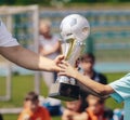 Passing of the Soccer Trophy Moment. Young Player Awarding Trophy Closeup. Child as a Team Captain Winning Sport Football Champion