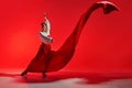 Passion in every step. Elegant woman, professional dancer performing flamenco against striking red background.