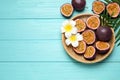 Passion fruits maracuyas, palm leaves and flowers on blue wooden table, flat lay. Space for text Royalty Free Stock Photo