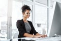 Passion keeps her one step ahead of the competition. a young businesswoman using a computer at her desk in a modern Royalty Free Stock Photo