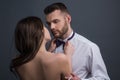 Passionate couple, romantic lovers. Woman holds mans bowtie, bow tie. Sexy elegant people in tender passion.
