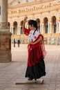 Passionate flamenco dancer woman in colorful clothes dancing at the Plaza de Espana in Seville