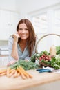 Passionate about food. A beautiful woman leans on her kitchen counter behing a basket of fresh vegetables. Royalty Free Stock Photo