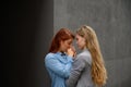 Passionate loving lesbian couple. Two beautiful young women hugging tenderly outdoors against a gray wall. LGBT commune